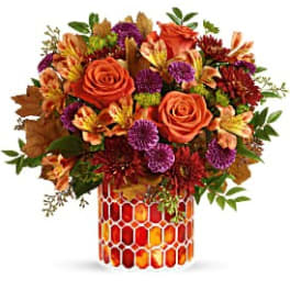 Orange roses and mixed fall flowers in a patterned vase