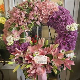 Large pink and purple funeral wreath with lilies and roses on an easel