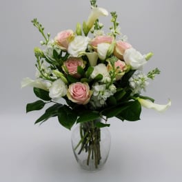 Pink and white roses with calla lilies in a clear glass vase