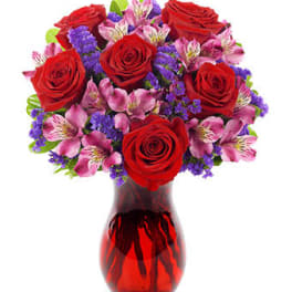 Bouquet of red roses and pink alstroemeria in a red glass vase