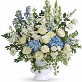White and blue floral arrangement in a white pedestal vase