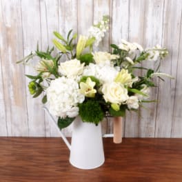 White and pale yellow flowers arranged in a white watering can