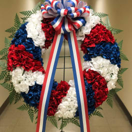 Red, white, and blue floral wreath with a patriotic ribbon bow