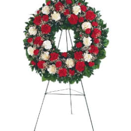 Standing floral wreath of red and white flowers on an easel