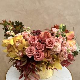 Mixed bouquet of pink roses and yellow orchids in a gold vase