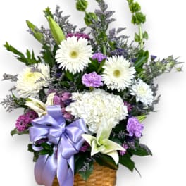 Basket arrangement of white and purple flowers with a lavender ribbon
