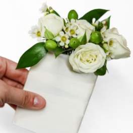 White floral corsage with green accents on a white card