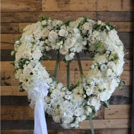 Heart-shaped wreath of white roses and daisies with a white ribbon