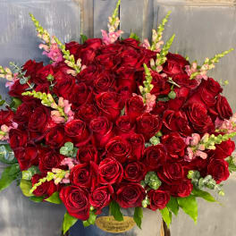 Large bouquet of red roses with pink snapdragons in a gray vase
