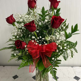 Red roses with baby's breath in a glass vase and red bow