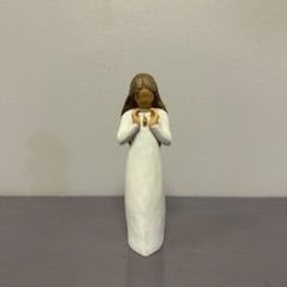Small angel figurine in a white dress holding a gold heart