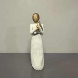 A small angel figurine in a long white dress holding a dove