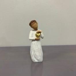 Small angel figurine in a white dress holding a gold heart