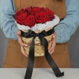 Basket of red roses wrapped with white paper and a black ribbon