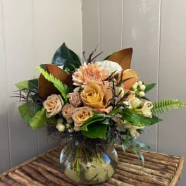 Mixed bouquet of peach and cream flowers in a glass vase