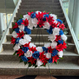 Large red, white, and blue floral wreath on a stand