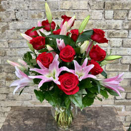 Red roses and pink lilies arranged in a clear glass vase