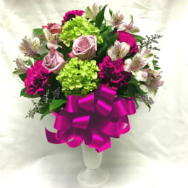 Bouquet of pink roses, green hydrangeas, and magenta carnations in a white vase