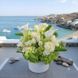 White and green floral arrangement in a white vase with calla lilies and roses