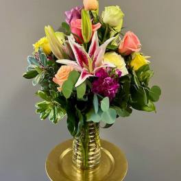 Mixed bouquet of roses and lilies in a gold vase