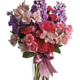 Bouquet of pink and purple flowers in a clear glass vase with a ribbon