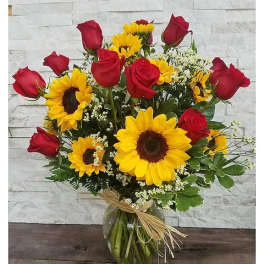 Bouquet of red roses and yellow sunflowers in a glass vase