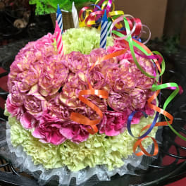 Round bouquet of pink and green carnations with ribbon curls and birthday candles