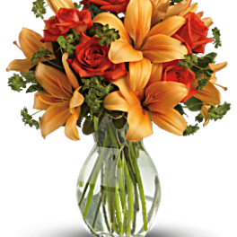 Orange lilies and red roses in a clear glass vase