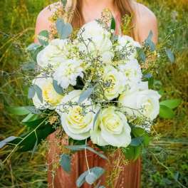 Bride holding a bouquet of white roses and pale blooms with eucalyptus