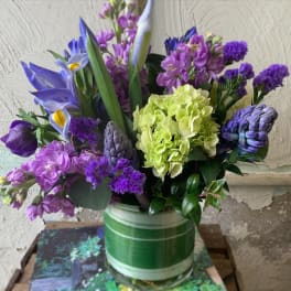 Purple and lavender mixed bouquet in a green striped vase