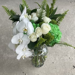 White orchids and roses in a glass vase with bright green hydrangea