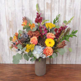 Mixed bouquet of orange and yellow flowers in a ribbed vase