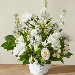 White and cream flowers including roses and mums arranged in a white woven basket