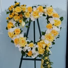 Heart-shaped floral wreath of yellow and white roses on an easel