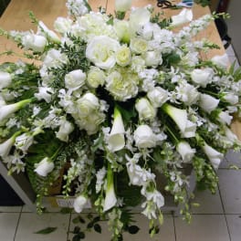 Large white floral arrangement with roses, calla lilies, and orchids