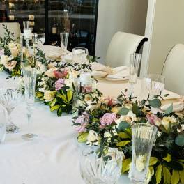 Floral garlands with pink and cream roses on a banquet table with glassware