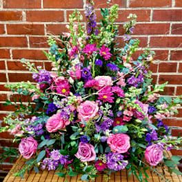 Large bouquet of pink and purple flowers arranged against a brick wall