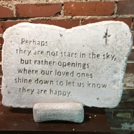 Stone memorial plaque with an engraved quote and star cutouts