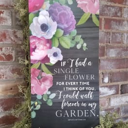 Floral wall sign with pink and purple blooms and a garden quote