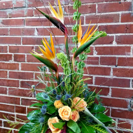 Tropical flower arrangement with orange roses and bird-of-paradise blooms