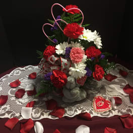 Heart-shaped floral arrangement with red, white, and pink flowers