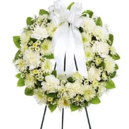 White floral funeral wreath on a standing easel with a ribbon bow