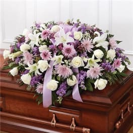 Lavender and white floral spray on a wooden casket