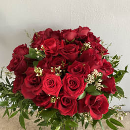 Bouquet of red roses in a glass vase with greenery
