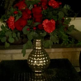 Red carnations in a gold vase with greenery
