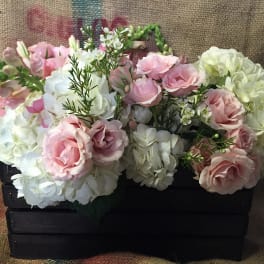 Pink and white floral arrangement in a black wooden crate