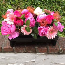 Pink floral arrangement in a black rectangular container