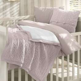 Pastel knit blanket and pillows arranged on a white crib
