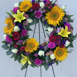 Colorful floral wreath with sunflowers, lilies, and roses on a black stand
