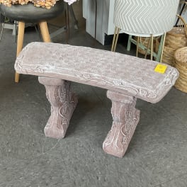 Pink velvet bench with carved legs in a shop display